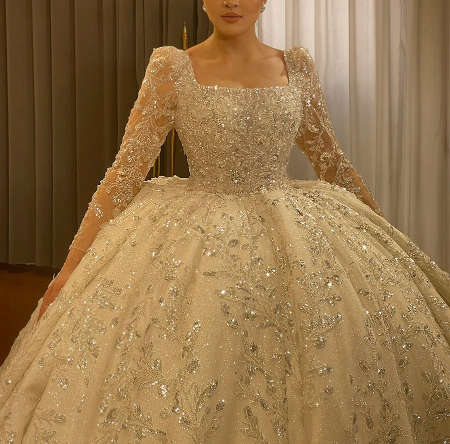 Close-up detail of the luxury bridal bodice, highlighting the intricate floral-patterned beading, silver sequins, and long-sleeve craftsmanship.