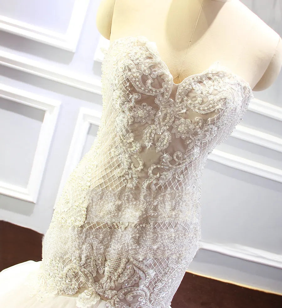 Side-profile view of the champagne mermaid wedding dress highlighting the fitted silhouette and the elegant transition from the beaded bodice to the flared skirt.