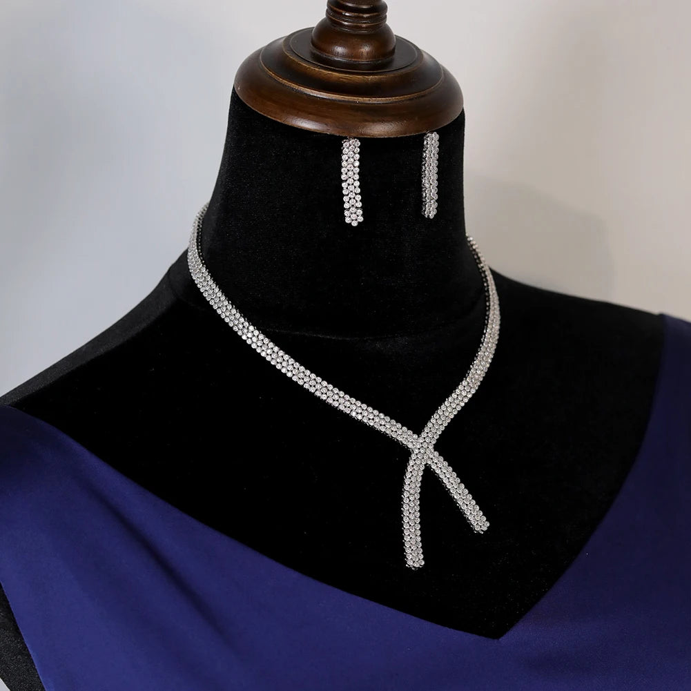 Side-profile view of the elegant multi-row crossover crystal bridal necklace and matching bar-style earrings on a velvet jewelry mount.