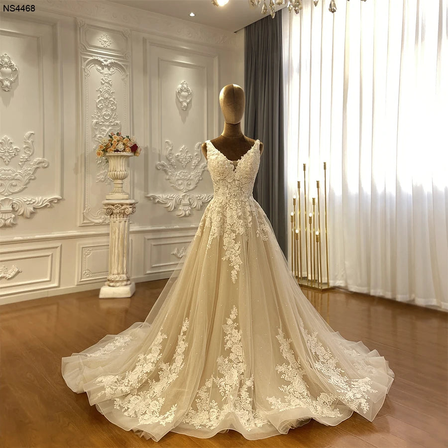 Full-length front view of a champagne V-neck beach wedding gown with white lace appliques displayed on a mannequin in a showroom.