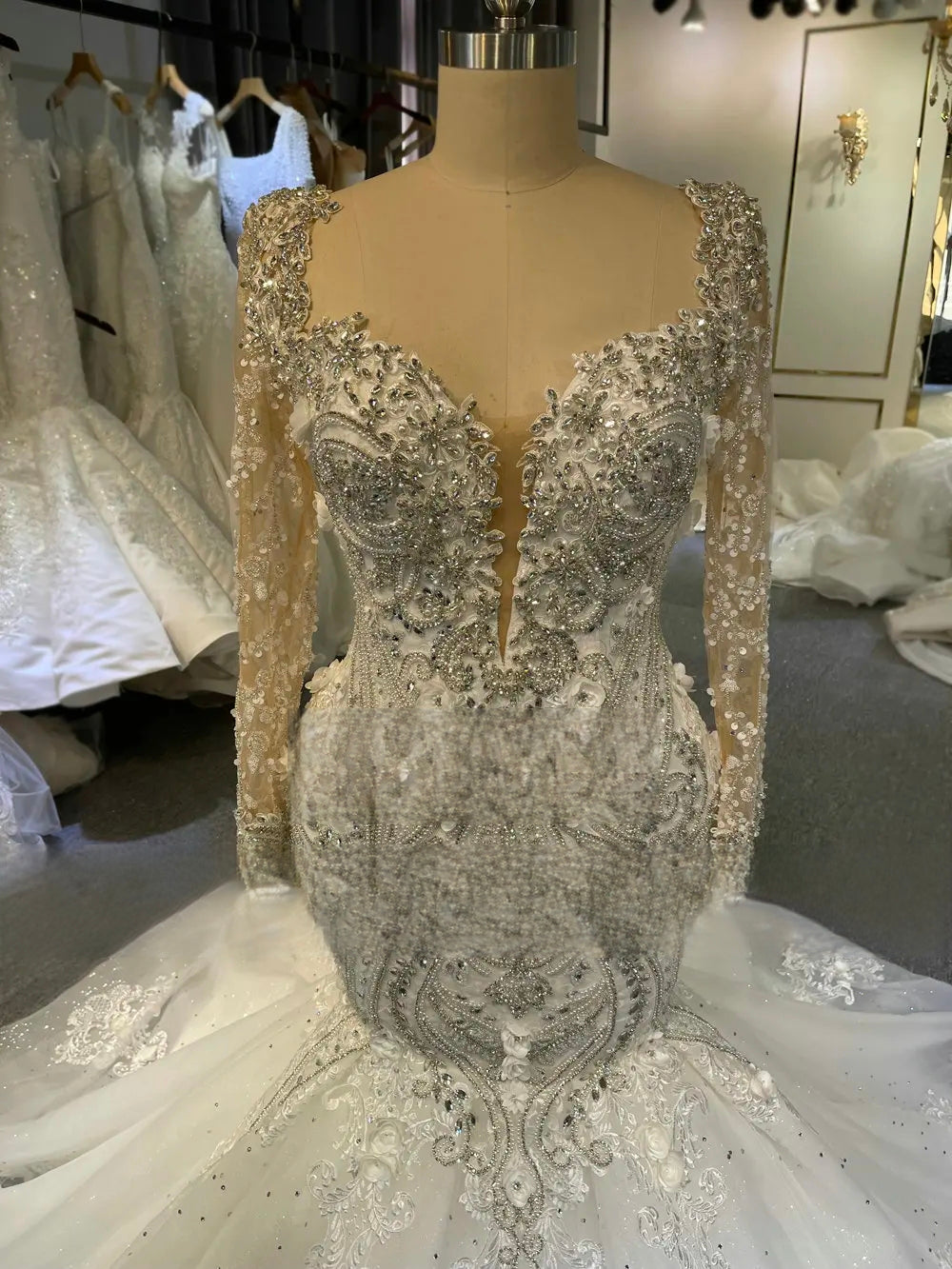 Close-up detail of the wedding gown’s bodice, featuring premium pearl and crystal embellishments on a sheer illusion neckline.