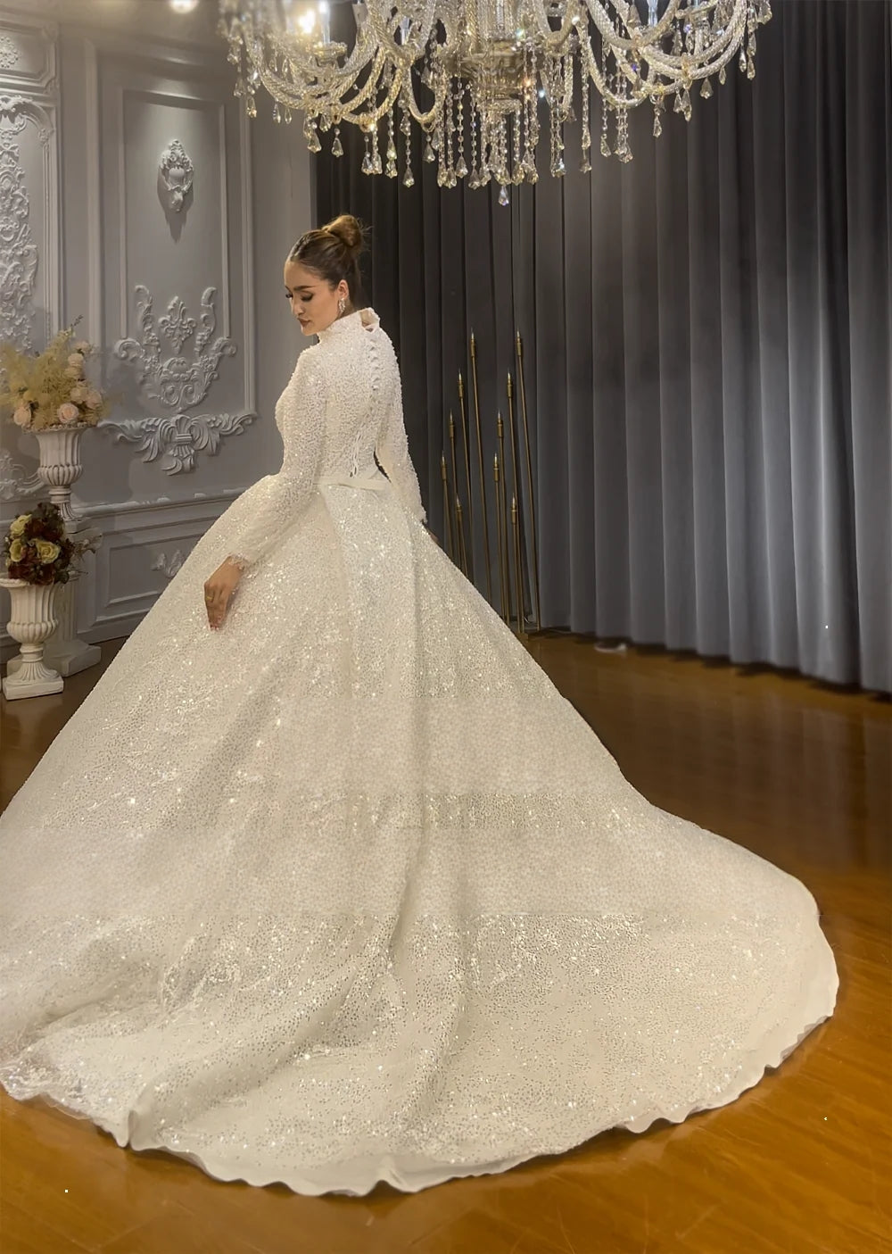 Elegant back view of a modest Muslim wedding dress with a high neckline and long sleeves, highlighting the expansive shimmering sequined train.