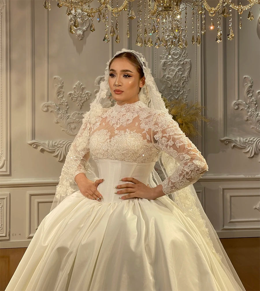 Close-up of a bridal gown bodice showcasing intricate 3D floral lace embroidery, a high neckline, and sheer long sleeves.