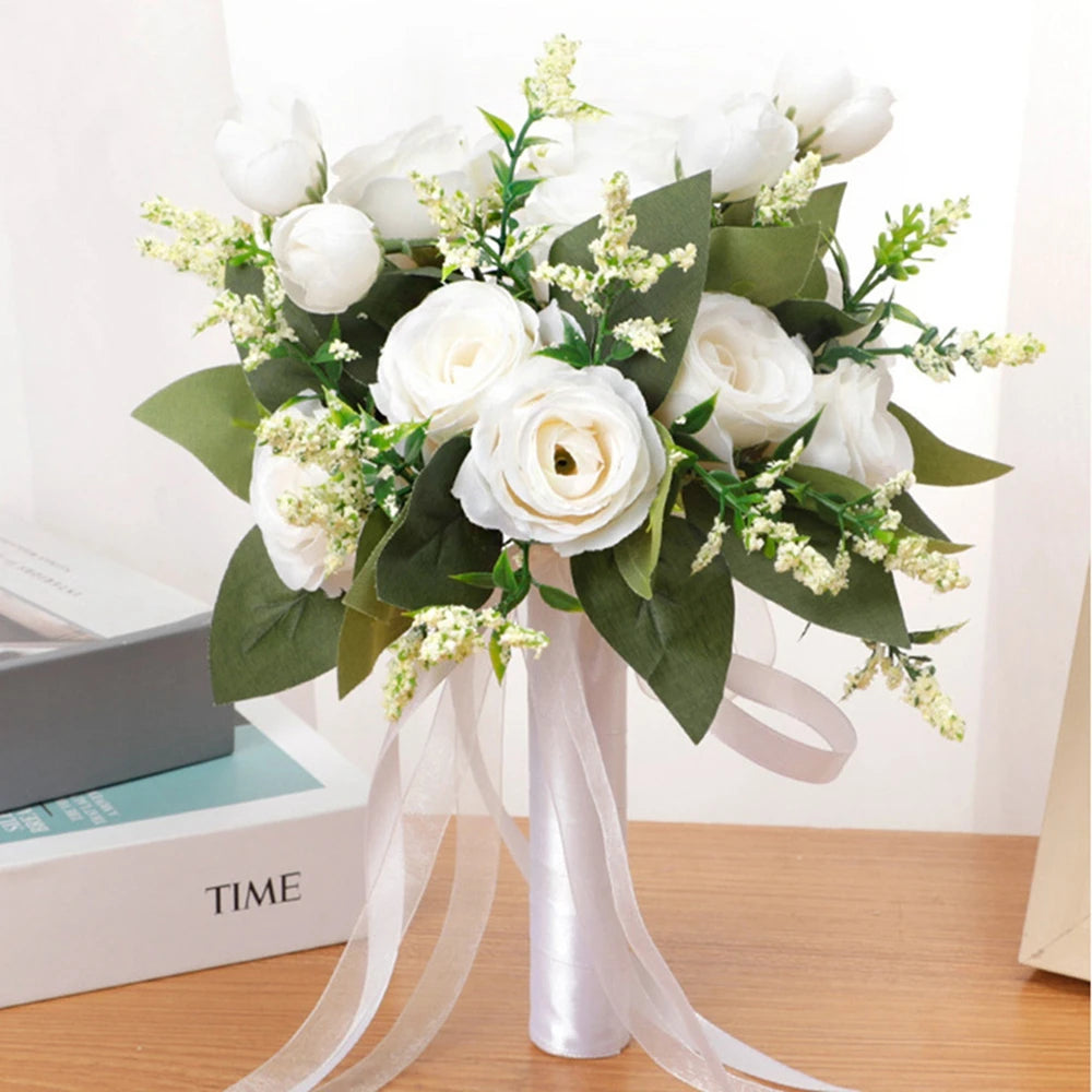 Direct view of a handmade white silk rose bridal bouquet adorned with green leaves, cream sprigs, and sheer ivory hanging ribbons.