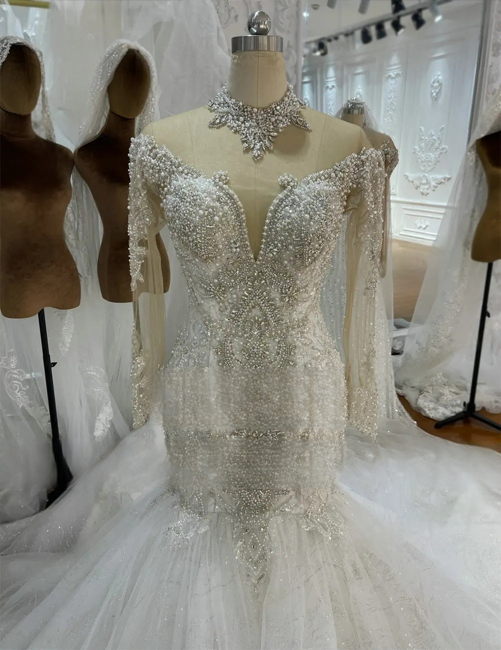 Close-up detail of the bodice on an elegant mermaid wedding dress, featuring exquisite pearl and crystal beadwork and a deep illusion V-neckline.