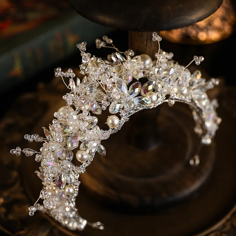 Top-down view of a flexible silver wire bridal tiara crown featuring pearl beads and multi-shaped crystal floral embellishments.
