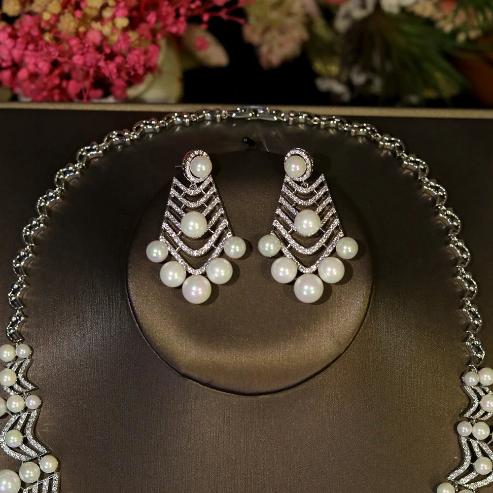 Detailed view of the elegant geometric cubic zirconia and pearl dropdown statement earrings on a display stand.