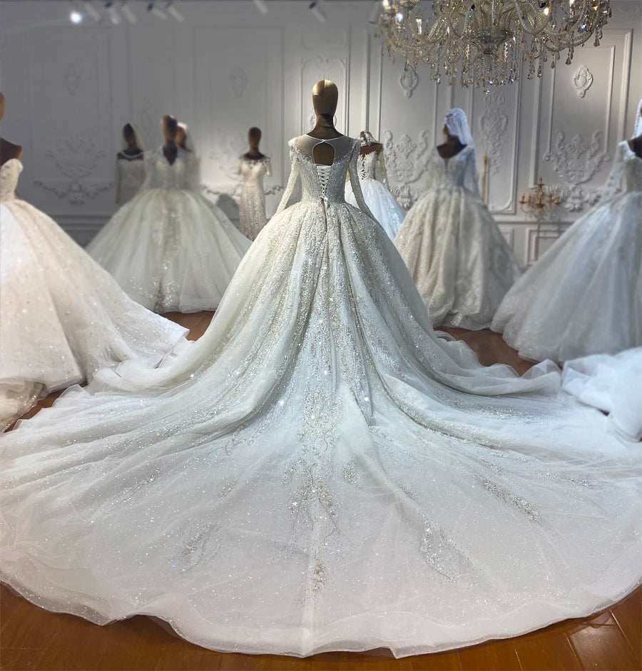 Rear view of a Dubai style bridal gown featuring an illusion keyhole back, traditional corset lace-up closure, and a massive sparkling cathedral train with premium detailing.