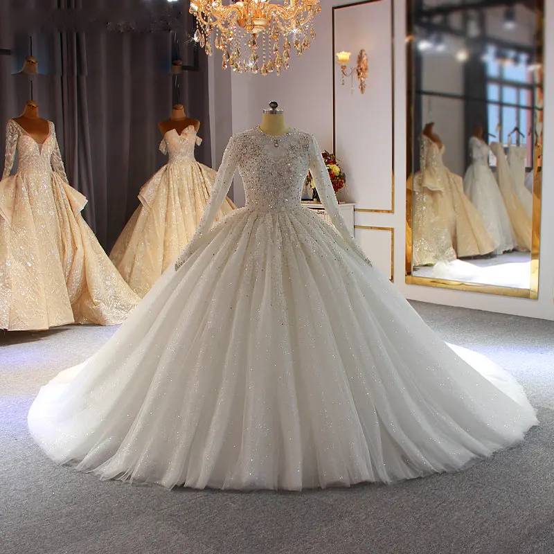 Front view of a luxury white Muslim bridal gown on a mannequin, showcasing the modest high-neck design, long sleeves, and shimmering crystal beading.