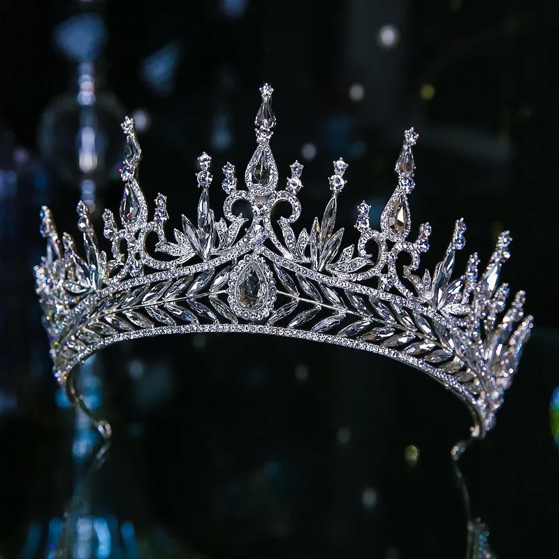 A tall, ornate silver crystal bridal crown featuring dramatic spires and intricate leaf vine filigree along the band.