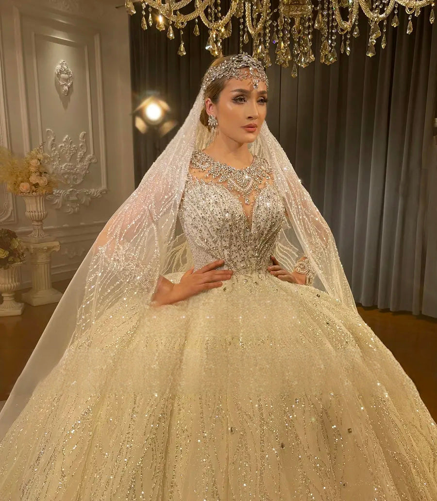 Close-up detail of a bride wearing a heavy beading bridal gown with an intricate crystal-embellished illusion neckline, matching headpiece, and a shimmering lace veil.