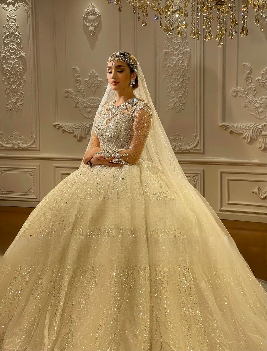 Close-up angled view of a model in a high-end beaded wedding dress, focusing on the detailed craftsmanship of the sleeves and the luxurious sparkle of the lace bodice.