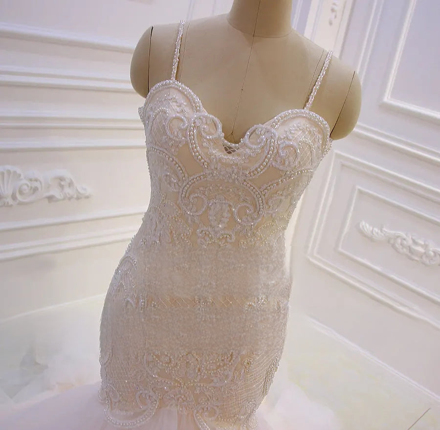 Close-up detail of the sweetheart neckline and heavily beaded lace bodice of a spaghetti strap mermaid bridal dress.