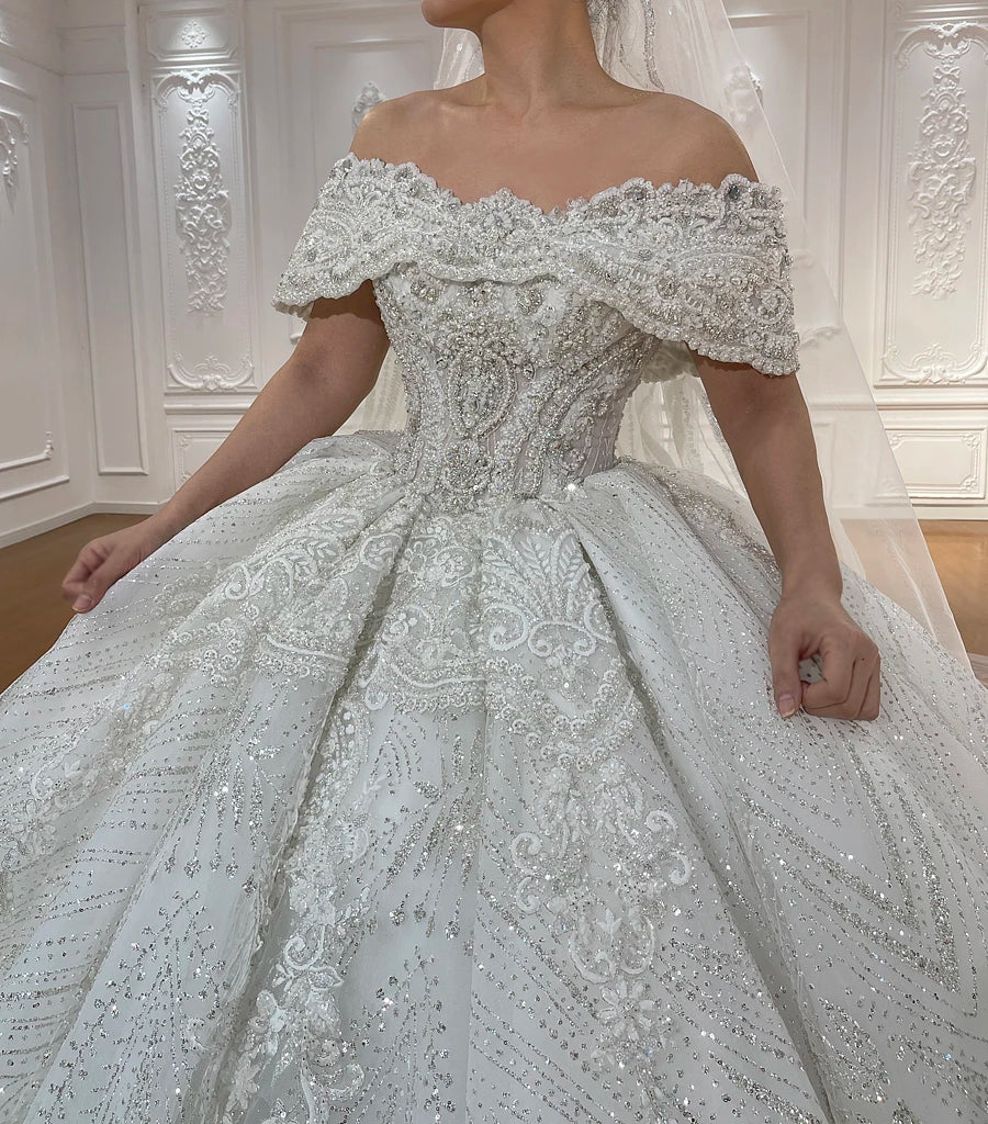 Close-up detail of a bridal gown bodice featuring off-the-shoulder lace straps, a sweetheart neckline, and intricate beadwork.