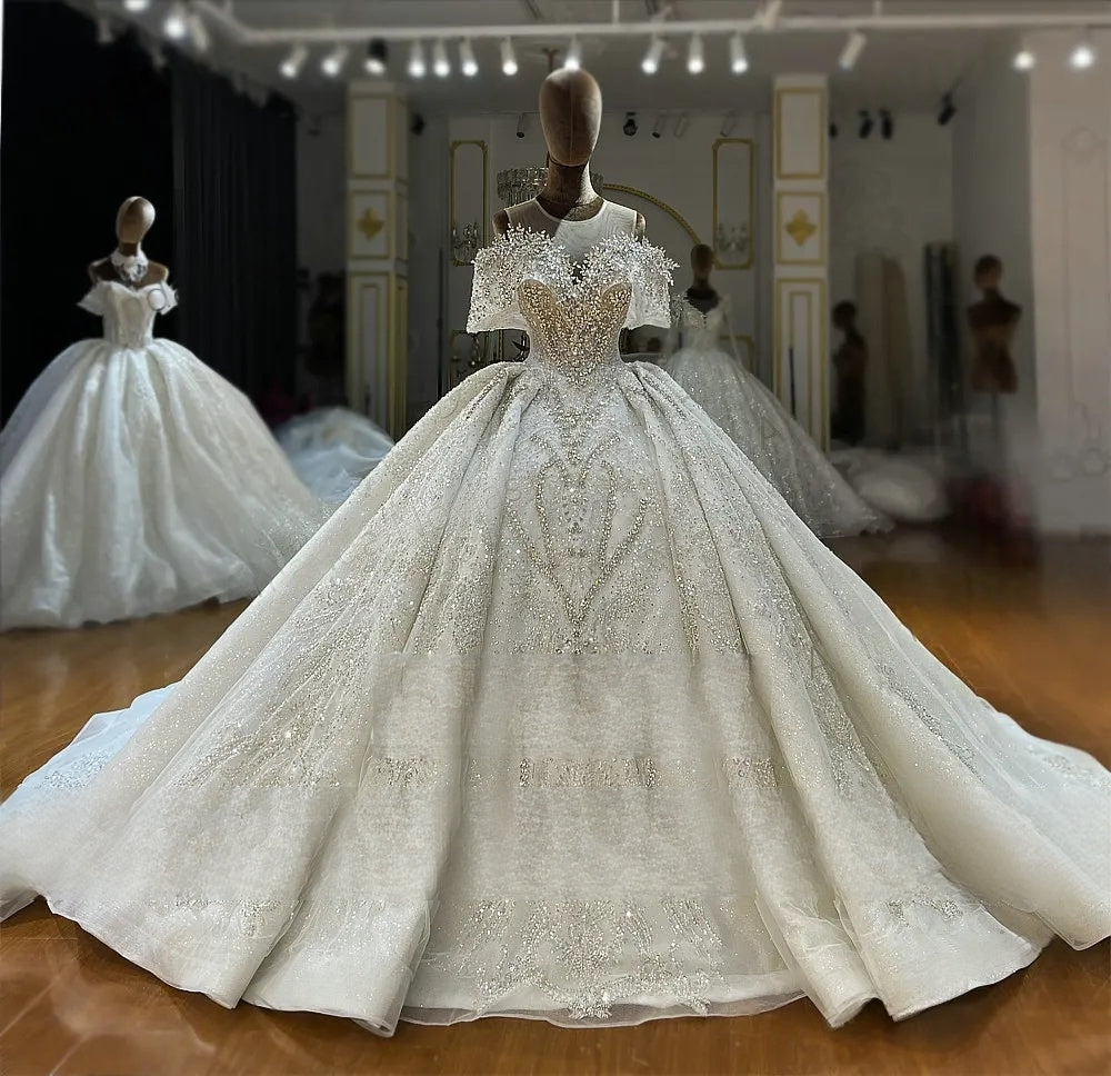 Full front angle view of the luxury off-the-shoulder beaded wedding gown displayed on a mannequin in a bridal showroom, emphasizing the expansive, sparkling skirt.