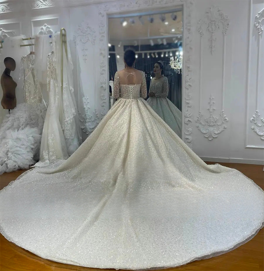 Rear view of the sparkling luxury bridal dress showcasing an illusion keyhole back, traditional corset lace-up detail, and a magnificent shimmering cathedral-length train.