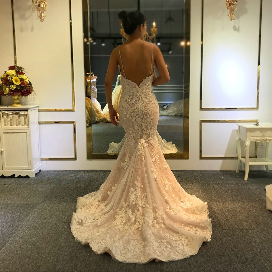 Back view of a lace mermaid wedding dress featuring a low V-back and a delicate floral lace train, shown in a bridal showroom.