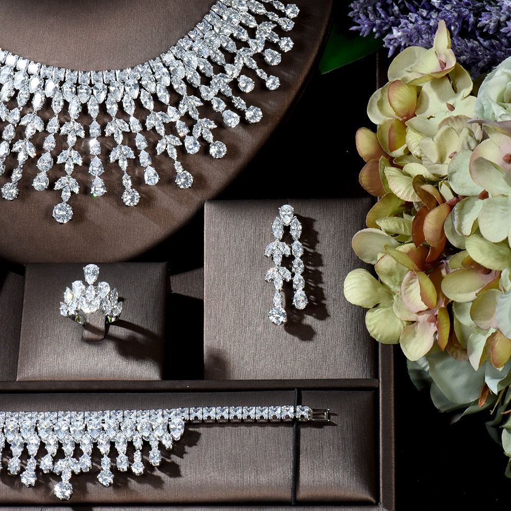 Detailed close-up photograph focusing on the lower section of the silver cubic zirconia bridal necklace, matching statement ring, and long drop earrings, beautifully framed next to light green and cream hydrangea flowers.