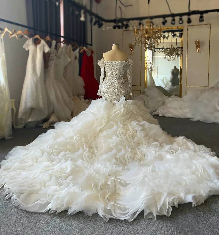 Frontal view of a shimmering long-sleeve mermaid wedding dress on a plus-size model, featuring dense silver beadwork and a royal-style detachable train.