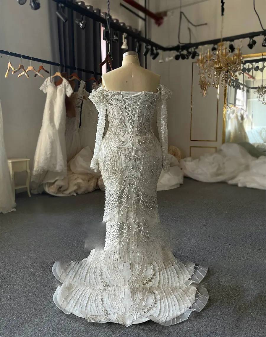 Close-up detail of the heavy crystal and pearl beading on a plus-size wedding dress bodice, emphasizing the high-end craftsmanship and shimmering texture.