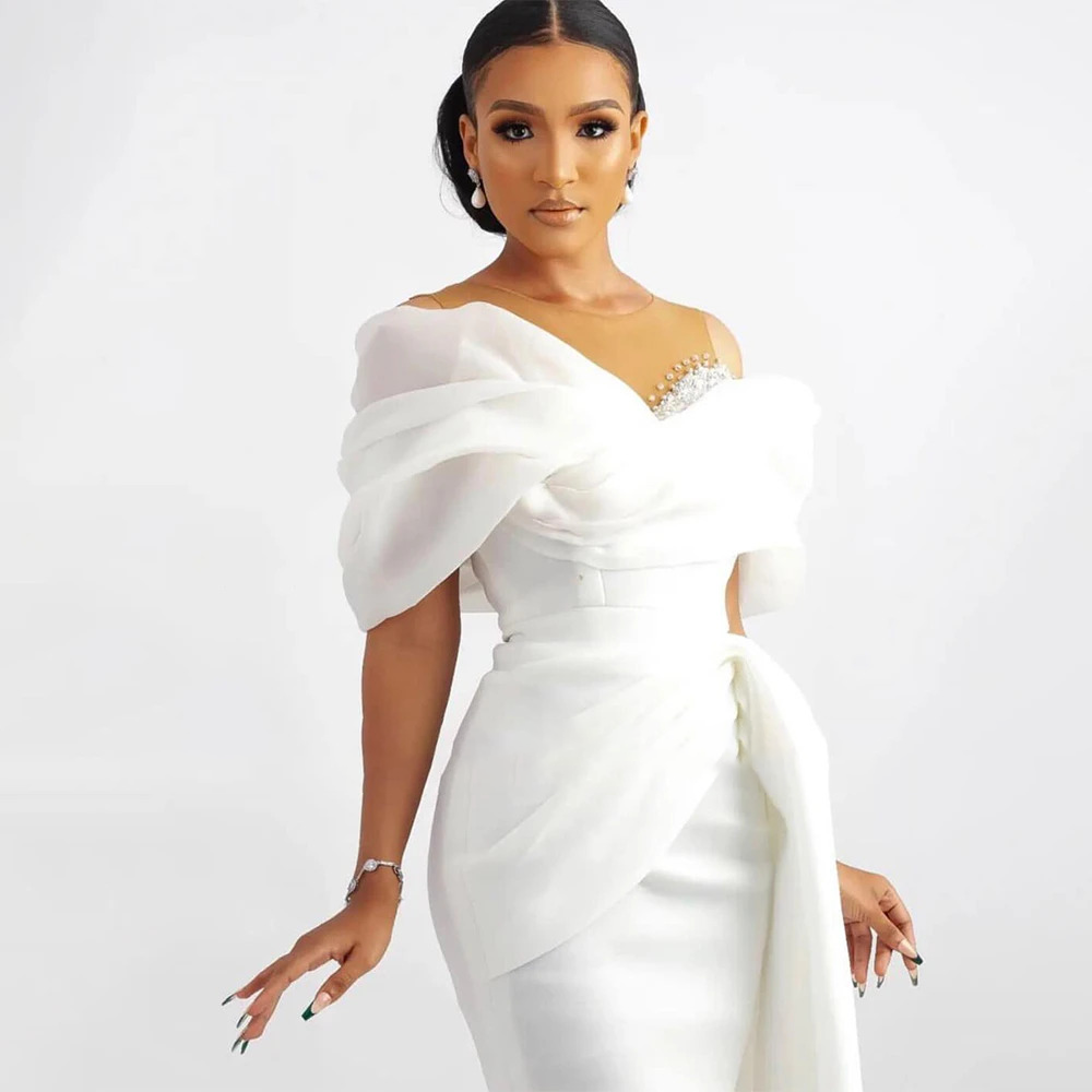 Close-up of a short bridal gown bodice highlighting the elegant draped off-shoulder detailing and fine hand-stitched beadwork along the illusion sweetheart neckline.