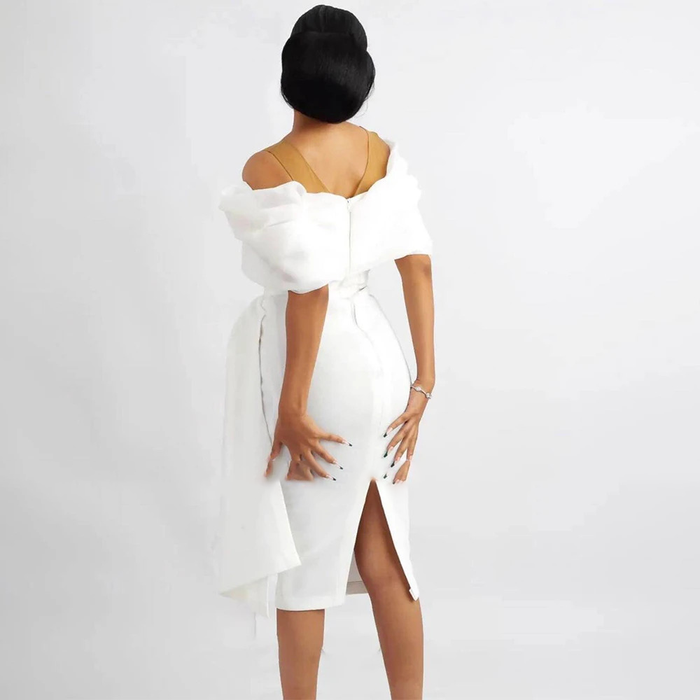 Rear view of a knee-length white rehearsal dinner dress showcasing a fitted sheath silhouette, a hidden zipper closure, and a classic walking vent slit.