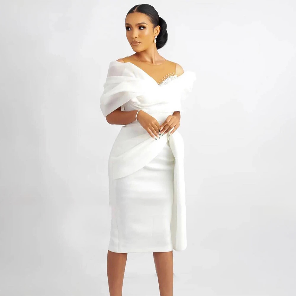 Chic off-the-shoulder white cocktail wedding dress with structural wrap-around fabric framing the bodice, ideal for a civil ceremony or bridal shower.