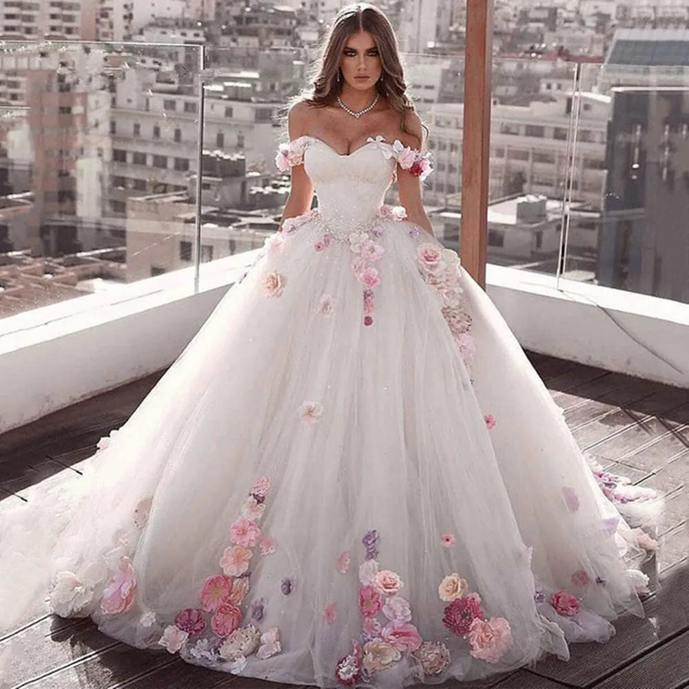 A princess wedding dress featuring a voluminous ball gown skirt, 3D floral accents, a sweetheart neckline, and an off-shoulder design.