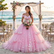 Smiling bride wearing a pink off-the-shoulder princess ball gown wedding dress with 3D flowers at a tropical beach ceremony altar.