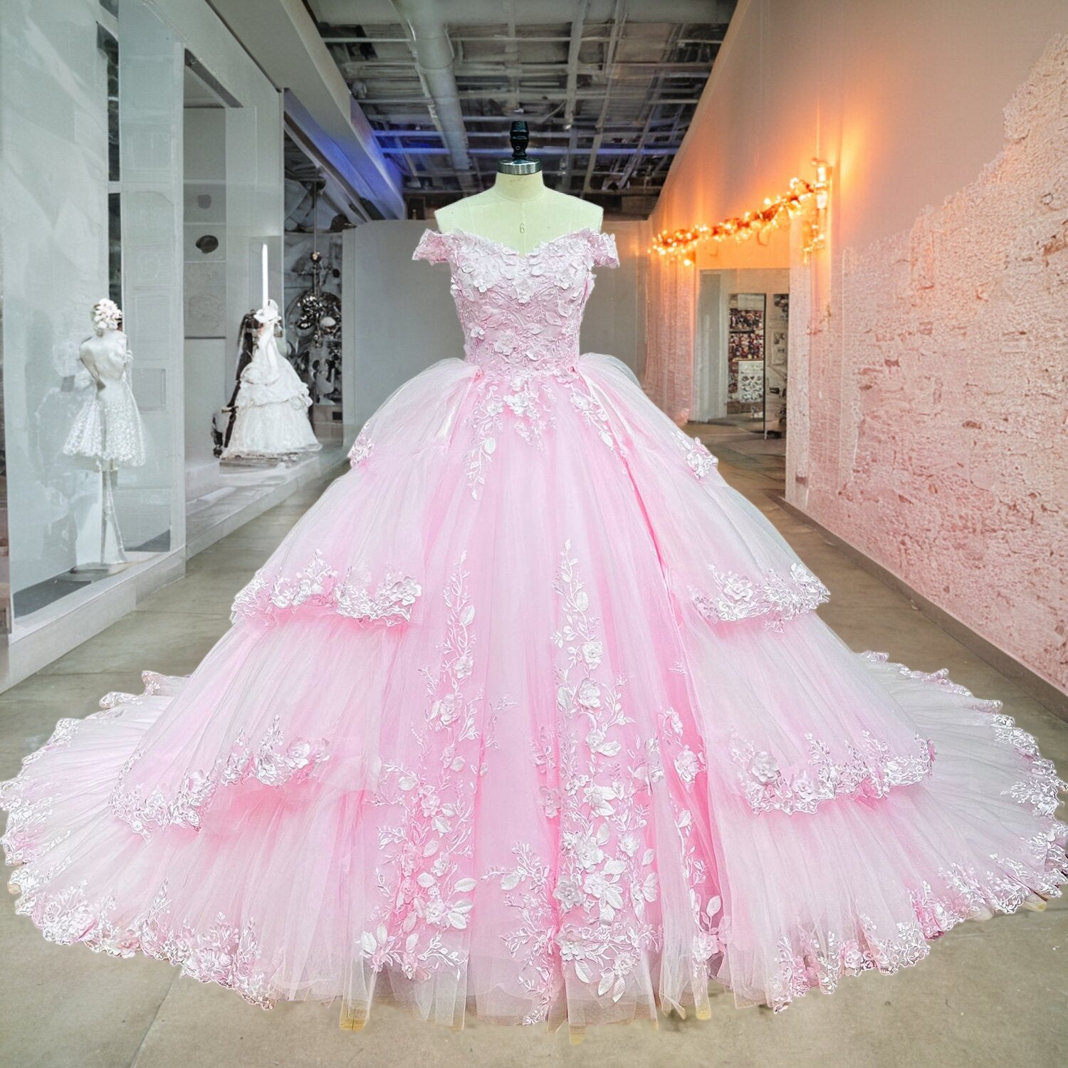 Full-length front view of a luxury pink princess ball gown wedding dress with a layered ruffle skirt on a mannequin.
