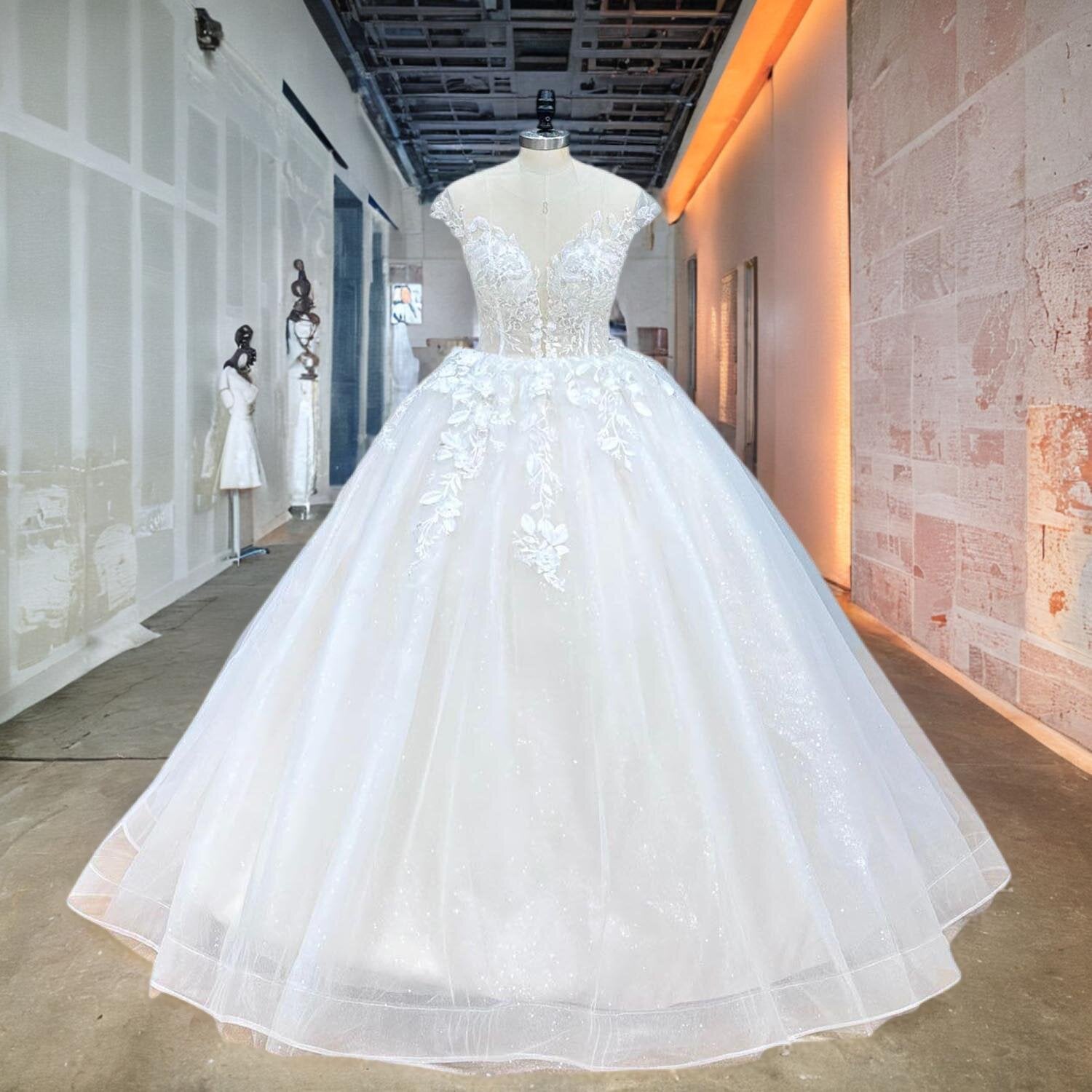Front view of a luxury vintage wedding dress on a mannequin, highlighting the sheer cap sleeves, illusion plunge neckline, and intricate 3D handmade flowers on the bodice.