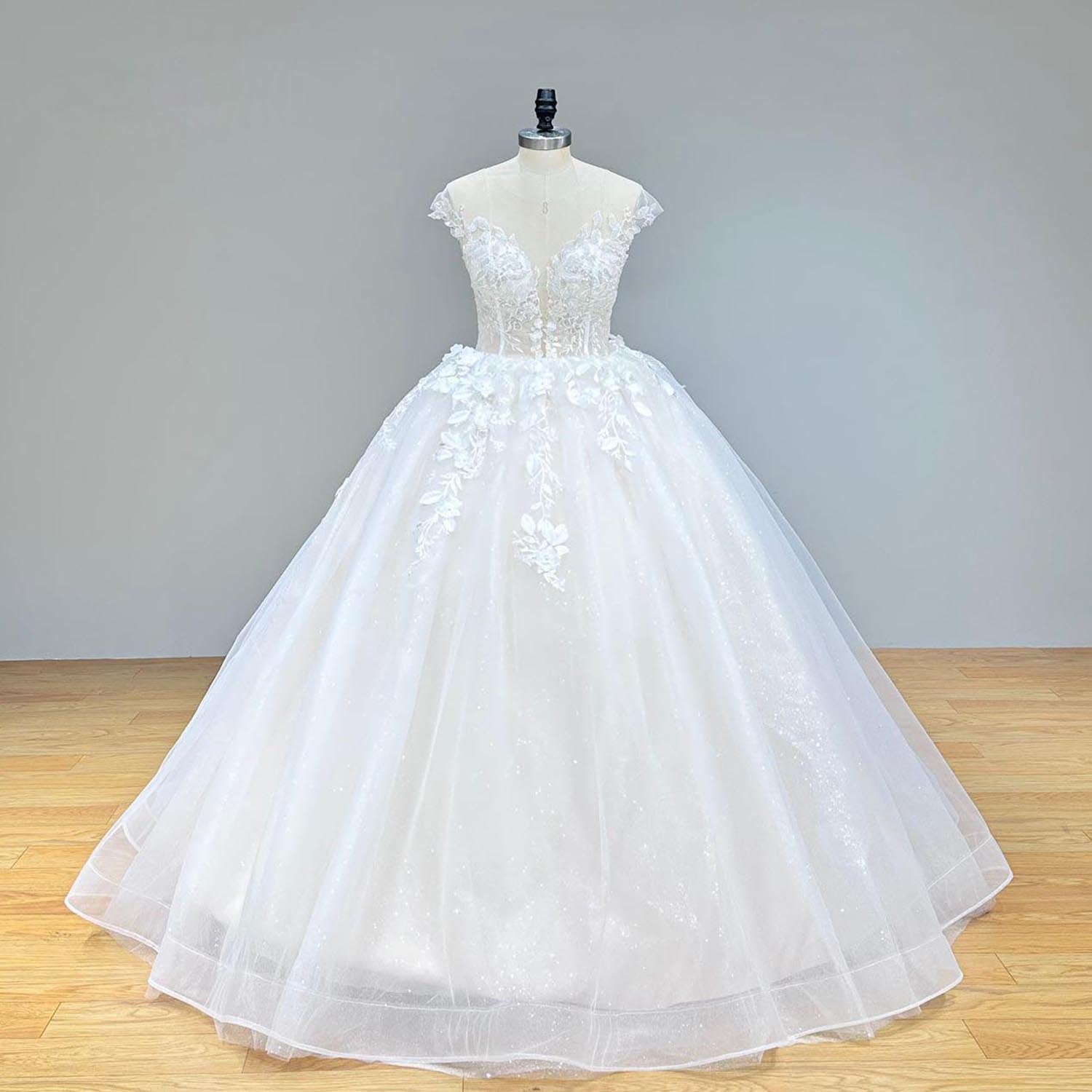 Full front view of a romantic, sparkling ballgown-style vintage wedding dress on a mannequin, showcasing the wide tulle skirt and detailed 3D handmade floral appliques.
