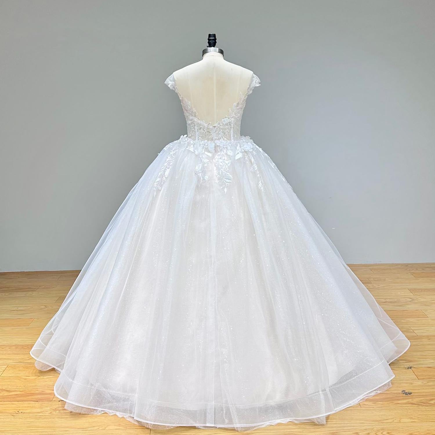 Full back view of a luxury backless vintage wedding dress on a mannequin, displaying the open sheer back, cap sleeves, and sweeping layered tulle skirt.
