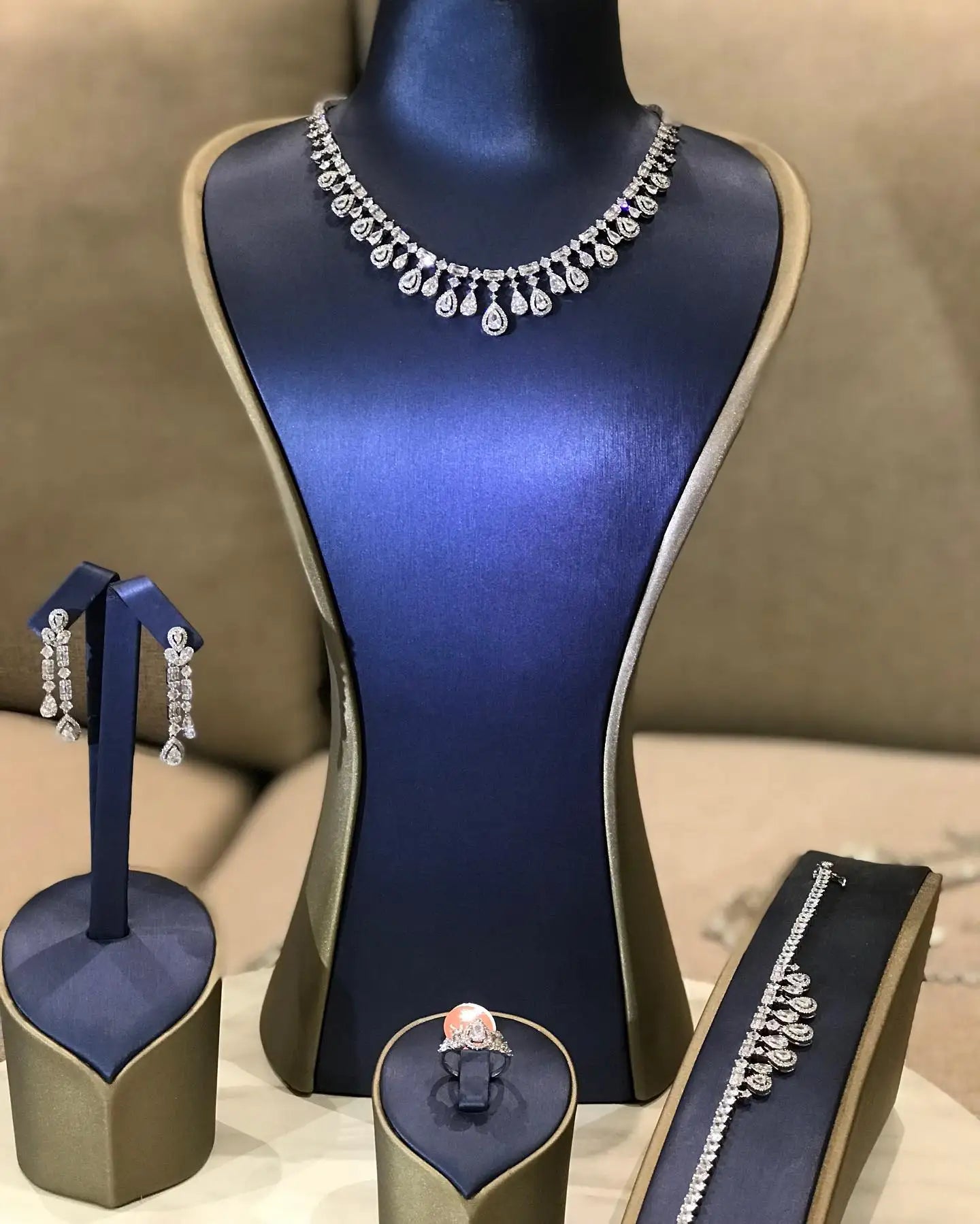 Premium 4-piece crystal bridal jewelry collection presented on a luxury blue and gold display bust with standalone earring and bracelet mounts.