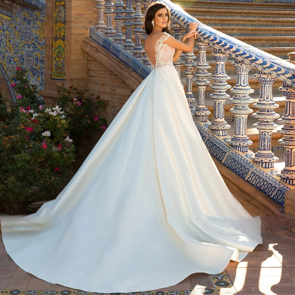 Back view of a bride wearing a vintage off-the-shoulder A-line wedding gown with long lace sleeves and a dramatic court train.