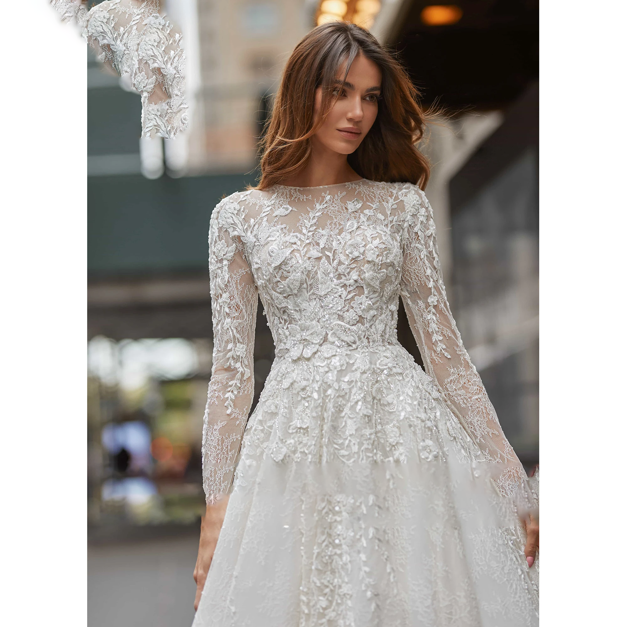 A close-up view of the bodice and long sleeves of an ivory A-line wedding dress, highlighting the delicate scoop neck, illusion sequinned beading, and floral lace.