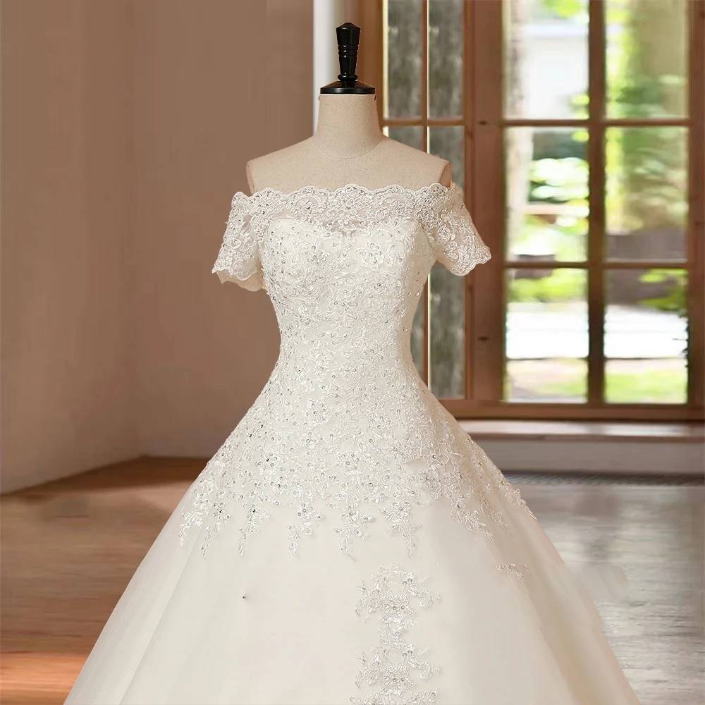 Close-up detail of a luxury bridal gown bodice showcasing intricate floral lace embroidery, delicate sequin beading, and an elegant off-the-shoulder short sleeve design.