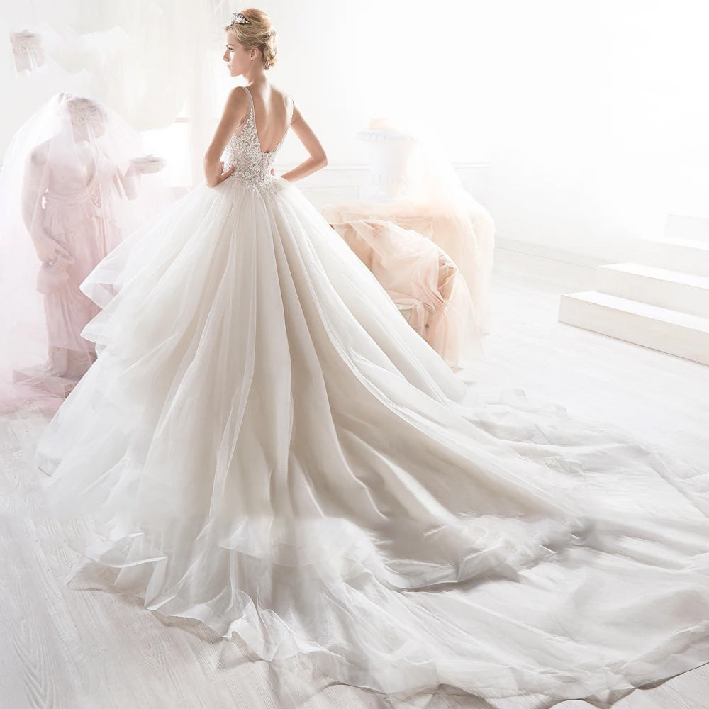 Back view of a stunning A-line bridal gown with a deep V-back, intricate beaded detailing, and a sweeping train.