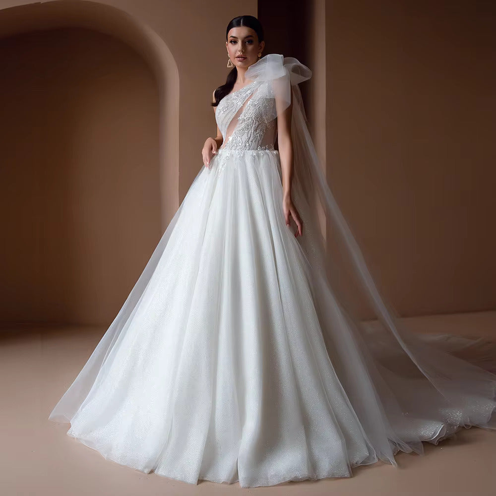 Full-length front view of a model wearing a luxury A-line off the shoulder wedding dress with a plunged sweetheart neckline, exquisite beading appliques, and a flowing tiered tulle skirt.