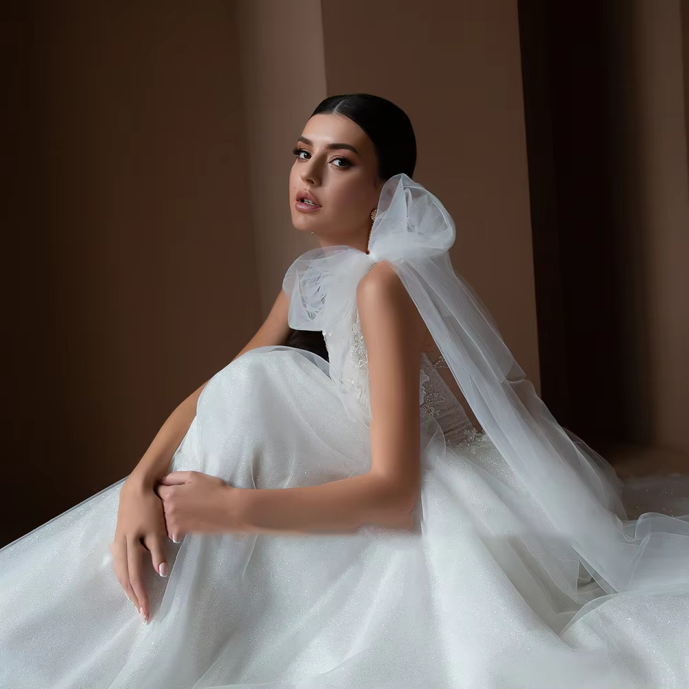 Close-up front view focusing on the intricate crystal beading appliques, floral embroidery, and romantic draped off-the-shoulder straps on the structured bodice.