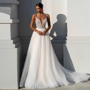 Beautiful bride modeling an A-line wedding dress with thin straps, a plunging sweetheart neckline, and a sweeping tulle skirt with a long train in a bright outdoor setting.