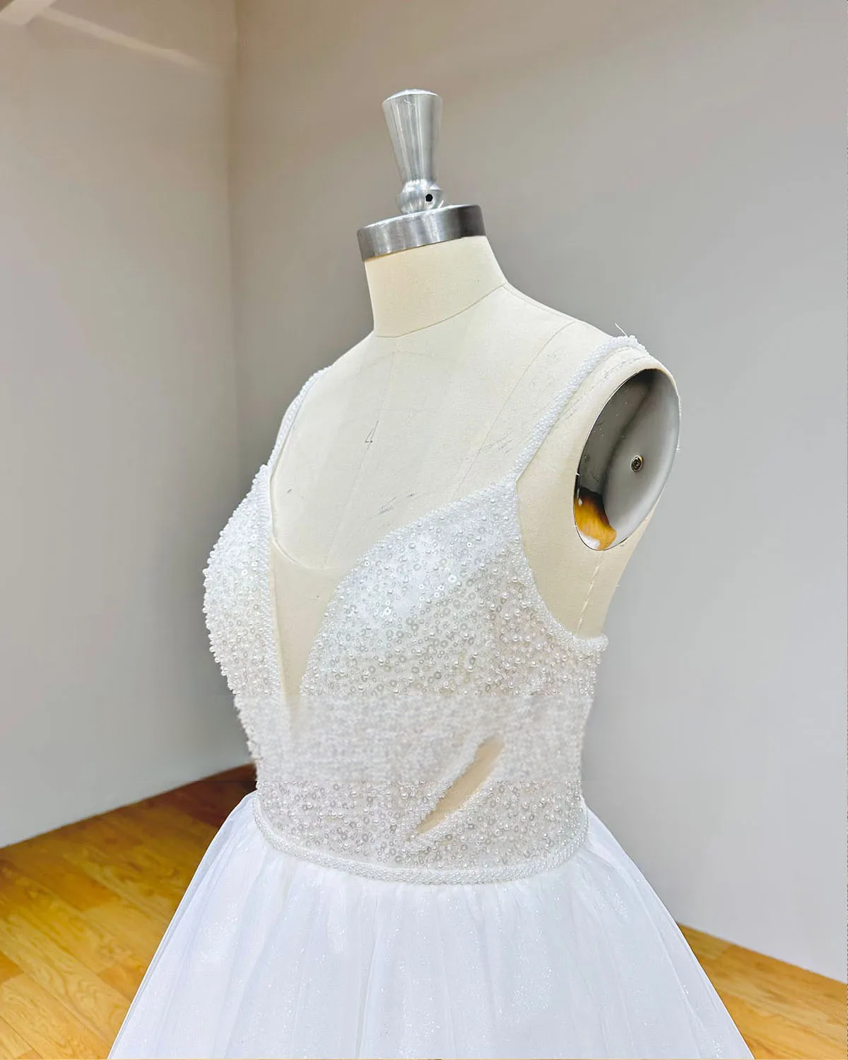 Detailed side profile of the beaded wedding dress bodice in showcasing handcrafted pearl patterns, sequins, and a modern sheer side cutout.