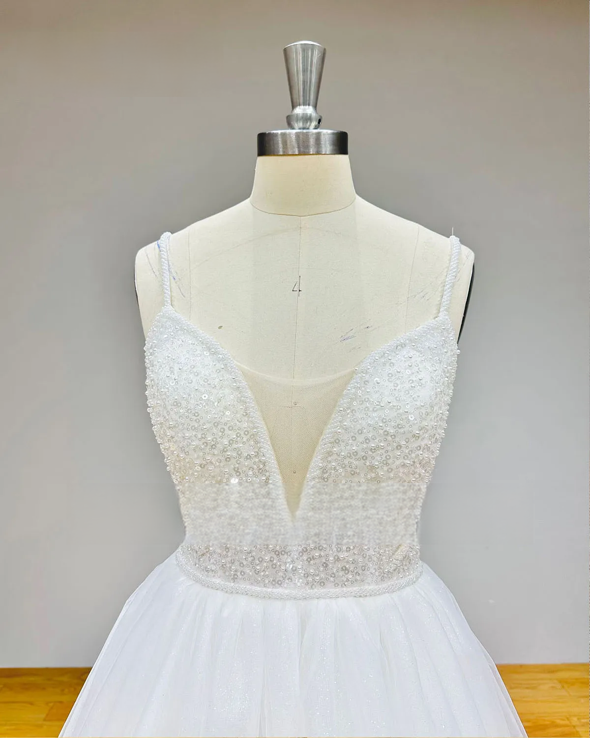 Detailed front view of the sweetheart neckline in accented with hand-sewn pearls and a deep plunging illusion mesh insert.
