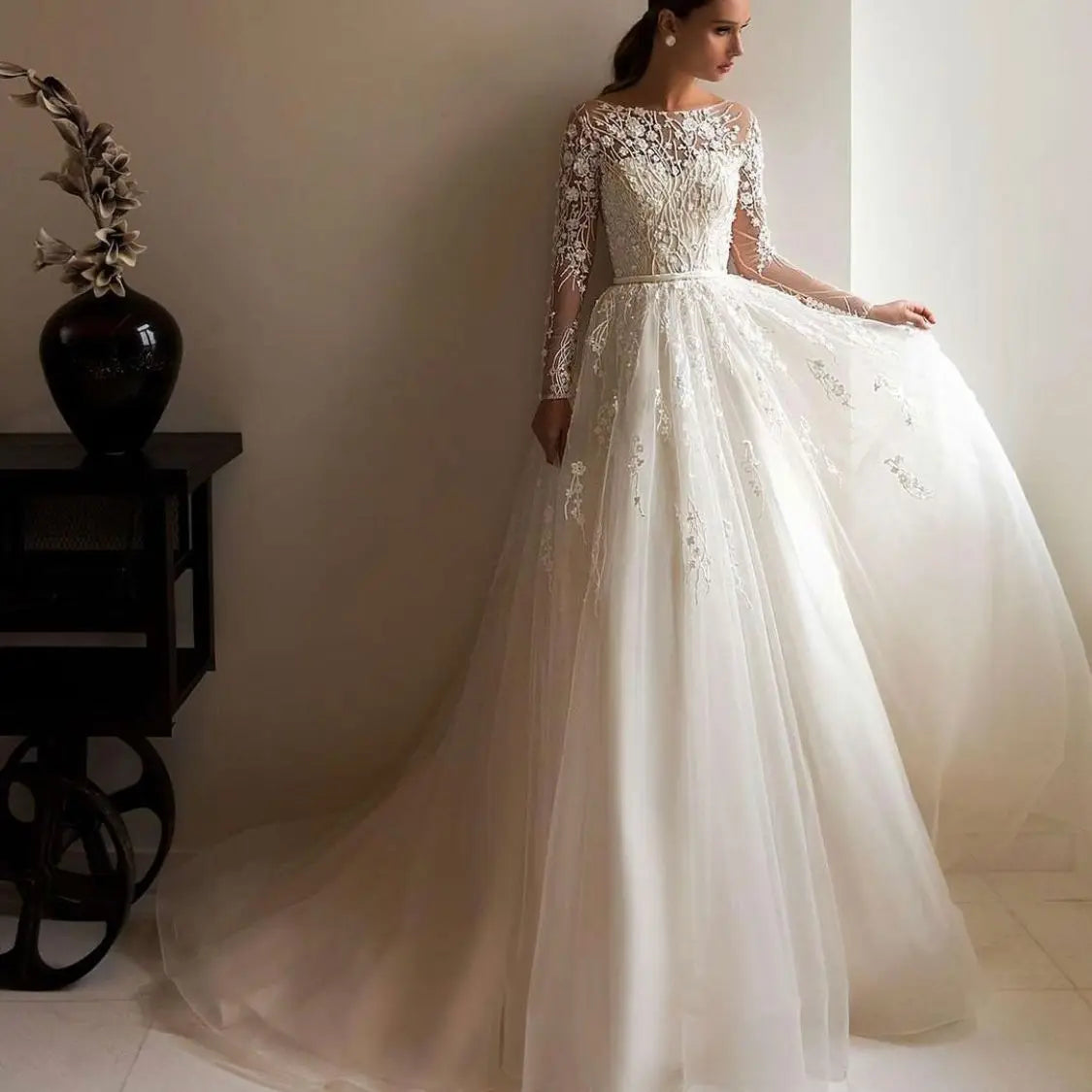 Full-length front profile of a sophisticated long sleeve A-line wedding dress in champagne tulle.