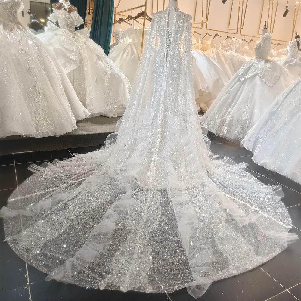 Full back view of the wedding dress on a mannequin, showcasing a row of elegant covered bridal buttons down the sheer lace back and a sweeping train.