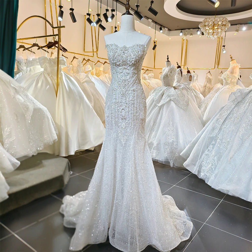 Side profile view of a structured A-line bridal gown, emphasizing the dramatic drape of the sheer sequined cape and the fluid movement of the tulle skirt.
