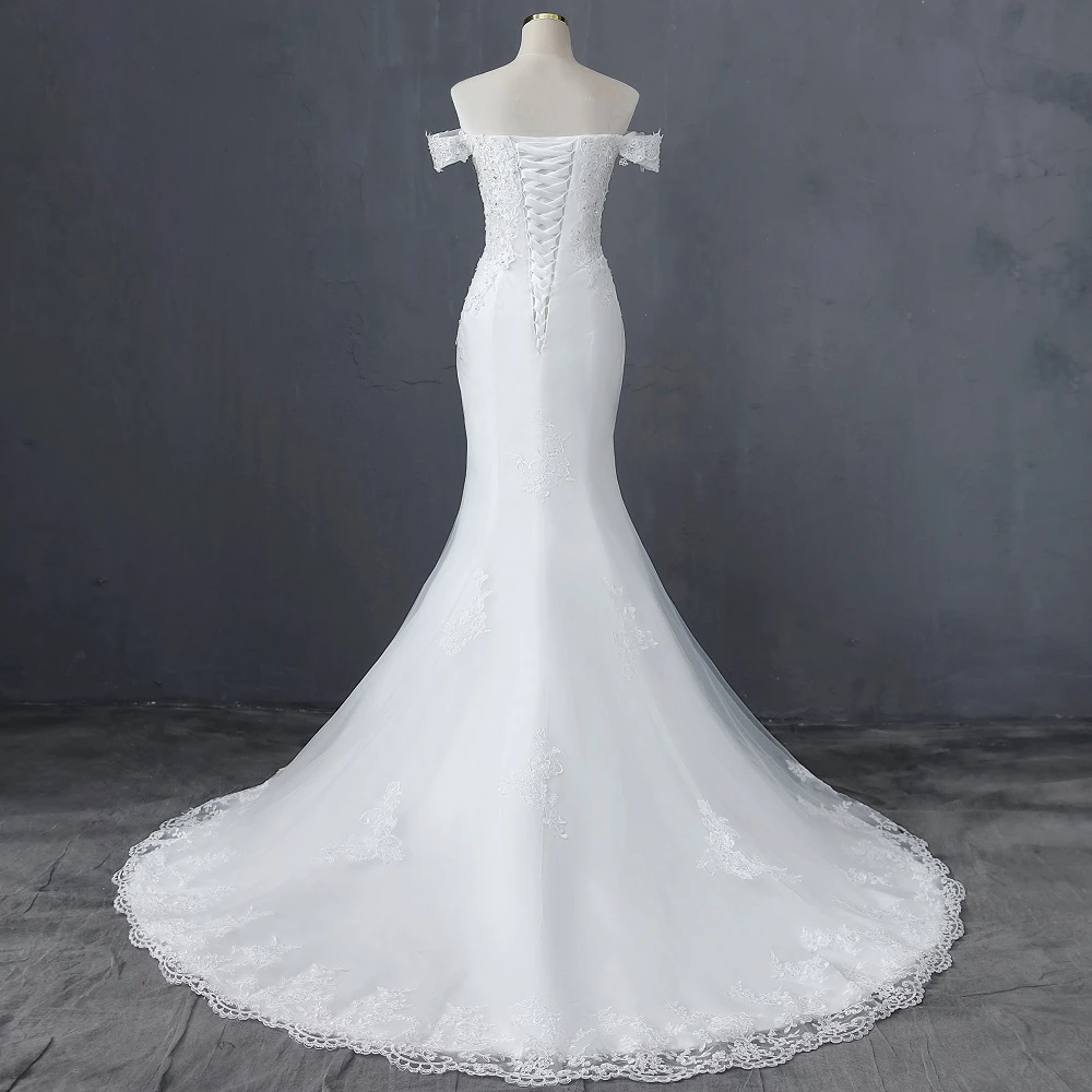 Mannequin display showing the back design of the boat neck mermaid wedding dress with its corset closure and elegant train.