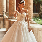 A bride wearing an elegant off-shoulder A-line wedding gown with intricate floral appliqué and a sweetheart neckline.