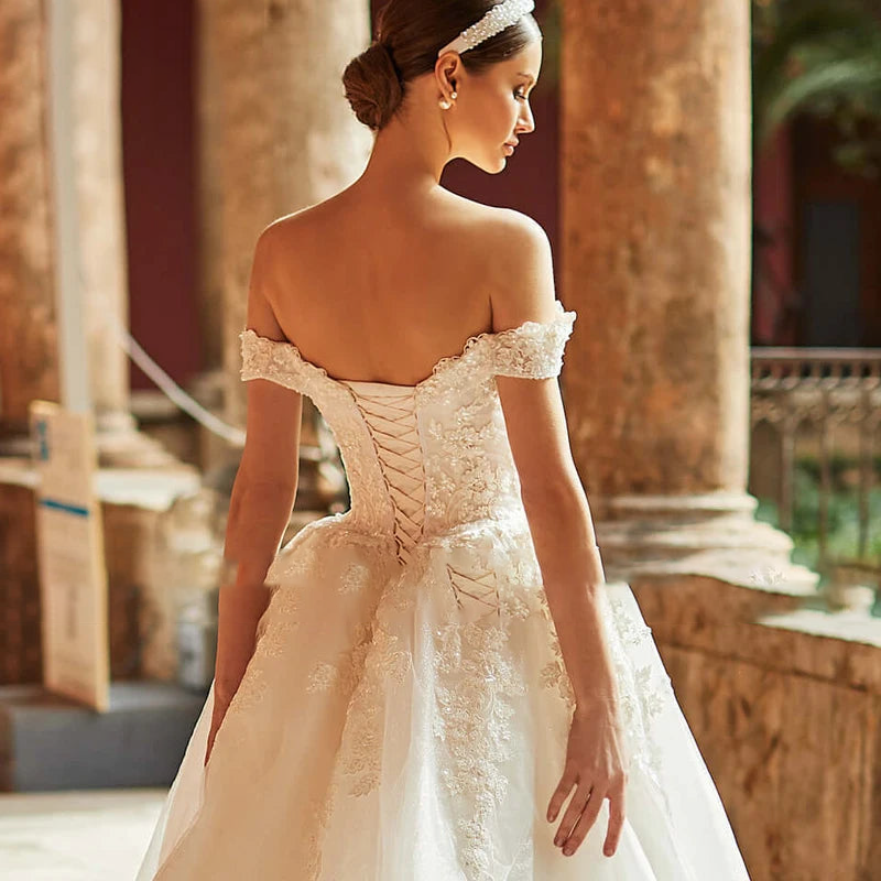 A portrait of a bride from behind, showcasing the intricate lace-up corset back and elegant flow of the A-line bridal gown.