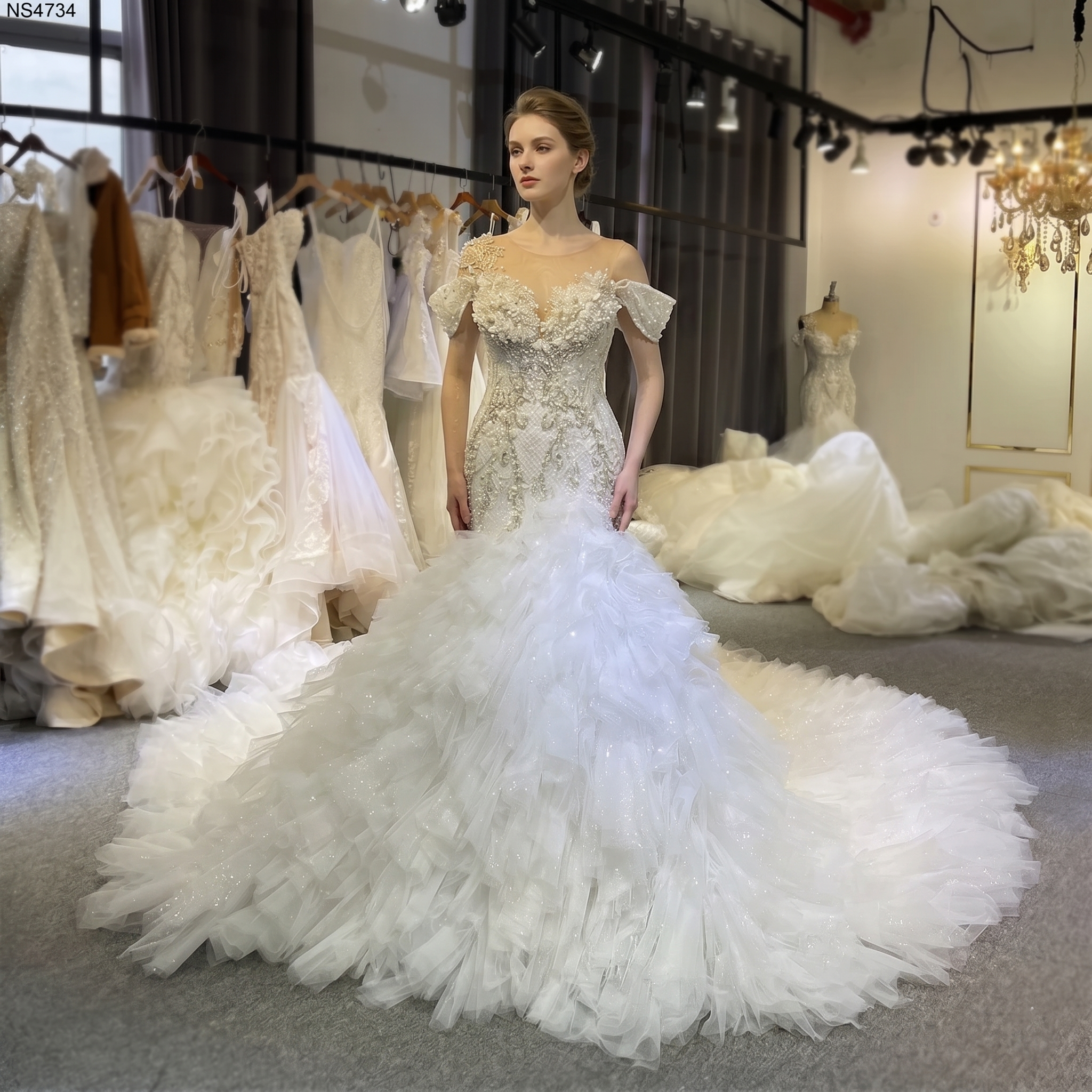 Front view of a model wearing an African mermaid handwork luxury wedding dress featuring an illusion neckline, intricate beadwork, and a voluminous ruffled tulle train.